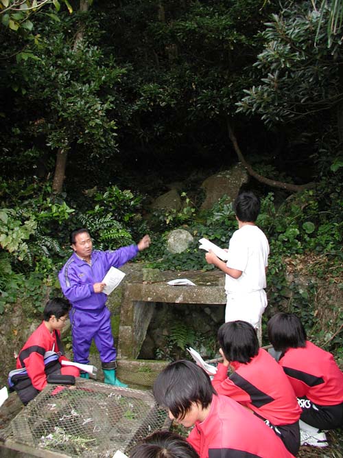 たんだの井戸をバックに米島区長から説明を受ける生徒たち
